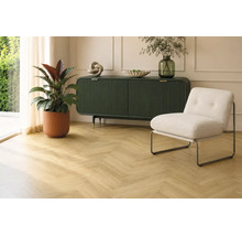 Wohnraum mit Eichenholzparkett im Fischgrätmuster, dunkelgrünem Sideboard, modernem Sessel und Zimmerpflanze in hellem Raum.