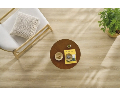 Draufsicht auf einen hellen Holzboden in einem modern eingerichteten Raum mit Sessel, rundem Holztisch, Zimmerpflanze und Dekoration.