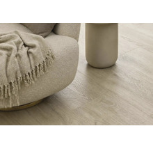 Heller Laminatboden mit natürlicher Holzoptik verlegt in einem Wohnbereich mit modernem Sessel und Beistelltisch.