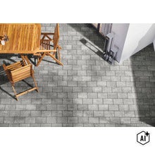 Eine Terrasse mit rechteckigen Pflastersteinen in Betonoptik, dazu ein Holztisch und Holzstühle als Gartenmöbel. (Image AI modified or generated)