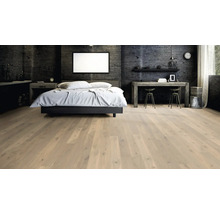 Helles Parkett in einem modernen Schlafzimmer mit Betonwand, Bett und Schreibtisch, vermittelt eine elegante und geräumige Atmosphäre.