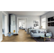 Helles Wohnzimmer mit Parkettboden im Fischgrätmuster, Kachelofen, Sofa und Couchtisch in einer modernen und freundlichen Atmosphäre.