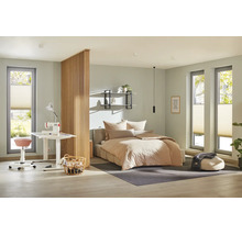 Ein modern eingerichtetes Schlafzimmer mit integriertem Arbeitsbereich, abgetrennt durch eine hölzerne Lamellenwand, mit Bett und Nähplatz.
