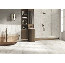 Modernes Badezimmer mit freistehender Badewanne, bodengleicher Dusche und Waschsäule, verkleidet mit Fliesen in Marmoroptik.