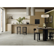 Moderne Wohnküche mit großer Kücheninsel, strukturierten Fronten und Essbereich mit dunklen Holzmöbeln und großflächigen Steinoptik Bodenfliesen.
