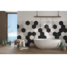 Modernes Badezimmer mit hexagonalen Wandfliesen und freistehender Badewanne vor einem Fenster mit Meerblick.