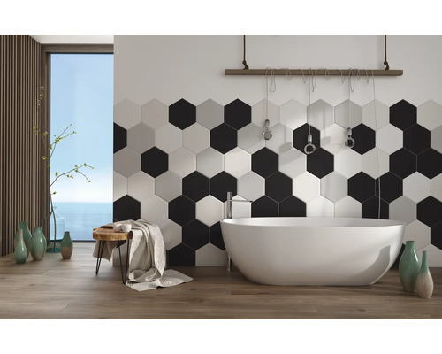 Modernes Badezimmer mit hexagonalen Wandfliesen und freistehender Badewanne vor einem Fenster mit Meerblick.