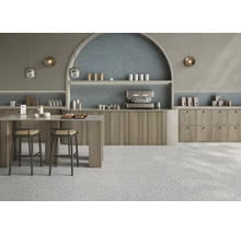 Moderne Café Einrichtung mit Terrazzo Fliesen an Boden und Wand sowie Holzschränken und einer bogenförmigen Wandnische mit indirekter Beleuchtung.
