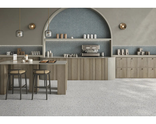 Moderne Café Einrichtung mit Terrazzo Fliesen an Boden und Wand sowie Holzschränken und einer bogenförmigen Wandnische mit indirekter Beleuchtung.