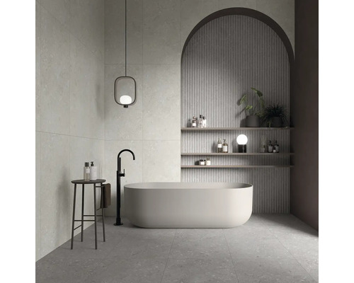 Modernes Badezimmer mit freistehender Badewanne, bodenstehender Armatur, dekorativer Wandnische mit Rundbogen und Regalen sowie stilvoller Leuchte.