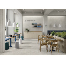 Modernes Café mit Steinfliesen an Wand und Boden, Holztischen, Holzstühlen und hängenden Leuchten in einem hellen, einladenden Innenraum.