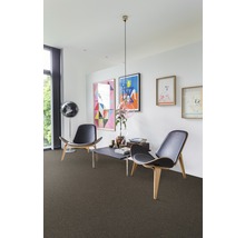 Wohnzimmer mit Teppichboden, zwei Stühlen und Kunstwerken an der Wand.