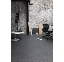 Innenraum mit dunklem Bodenbelag, Bürostuhl und weißem Tisch vor einer Ziegelwand