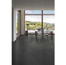 Heller Raum mit großem Fenster, Tisch und dunklem Boden aus Fliesen.