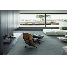 Modernes Wohnzimmer mit Fliesenboden, Sessel und Blick auf eine Terrasse.