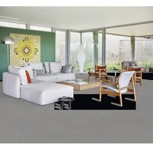 Heller Wohnraum mit grauen Bodenfliesen, Sofa und Holzstühlen