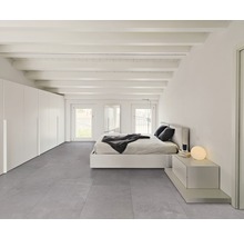 Helles Schlafzimmer mit Bett, Nachttisch, Kleiderschrank und grauem Bodenbelag