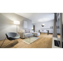 Helles Wohnzimmer mit Sofa, Sessel, Stehlampe und Esstisch