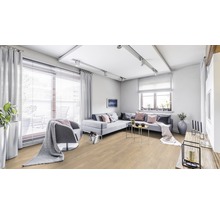 Heller Wohnraum mit Sofa, Sessel, Fenstern und Holzboden