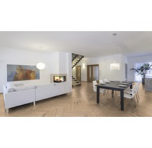 Helles Wohnzimmer mit Parkettboden im Fischgrätmuster, Sofa, Esstisch und Treppe