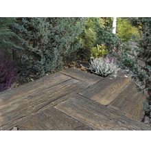 Gartenweg aus Holzpflastersteinen in Fischgrätmuster, umgeben von Pflanzen