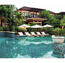 Swimmingpool mit Liegestühlen und Sonnenschirmen vor einem Gebäude