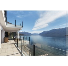Terrasse mit Glasgeländer und Blick auf den See und die Berge