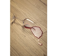 Umgefallenes Weinglas auf einem Holzboden mit ausgelaufenem Wein