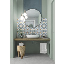 Badezimmer mit Waschbecken, Spiegel, gemusterten Fliesen und Holzhocker