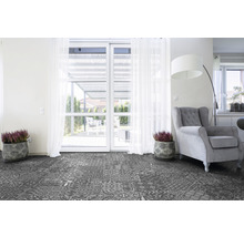 Wohnzimmer mit gemustertem Vinylboden, Sessel und Topfpflanzen vor einer Terrassentür