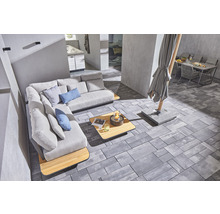 Außenbereich mit Ecksofa, Tisch, Feuerstelle, Sonnenschirm und Gartentisch mit Stühlen auf Pflastersteinen