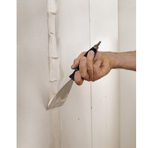 Hand verspachtelt Fugen an einer Gipskartonwand mit einem Spachtel
