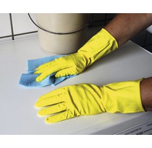 Reinigungskraft mit Gummihandschuhen und Putzlappen reinigt Oberfläche