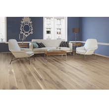 Heller Wohnraum mit Holzboden, Sofa und Sesseln für ein gemütliches Ambiente.