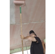 Mann streicht Decke mit Farbroller an Stiel