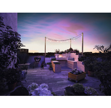 Dachterrasse mit Grill, Holzmöbeln, Bepflanzung und Lichterkette bei Dämmerung