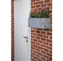 Blumenkasten aus Beton an einer Ziegelmauer neben einer Tür