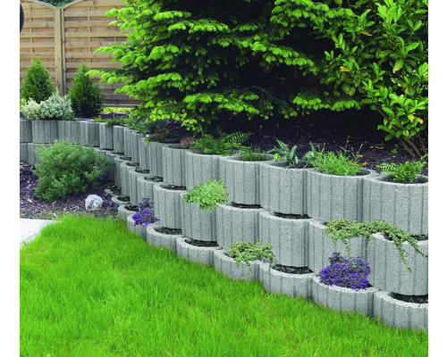 Gestufte Gartenanlage mit grauen Pflanzsteinen und grünen Pflanzen