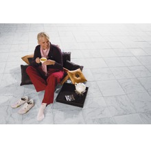 Frau sitzt mit Tasse Tee auf dem gefliesten Boden