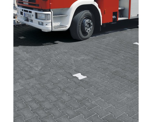 Graue Betonpflastersteine mit Feuerwehrwagen im Hintergrund.
