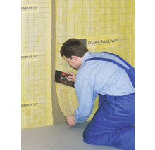 Handwerker trägt Abdichtungssystem Durabase WP mit einer Glättekelle auf die Wand auf