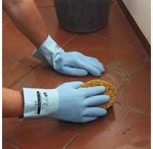 Eine Person wischt mit Schwamm und Schutzhandschuhen einen Fliesenboden.