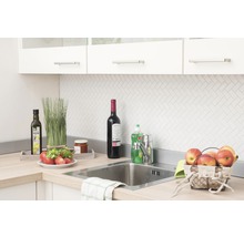 Küchenszene mit Spüle, Armatur und verschiedenen Küchenutensilien auf der Arbeitsplatte.