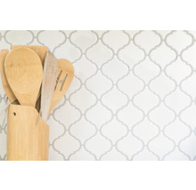 Küchenutensilien aus Holz in Halter vor gemusterter Wand