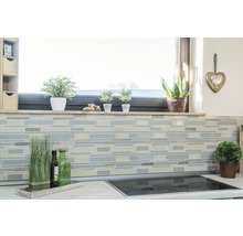 Küchenszene mit Fliesenmosaik an der Wand, Fensterbank mit Dekoration und Kochfeld auf der Arbeitsplatte.