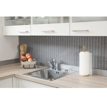 Küchenspüle aus Edelstahl mit Armatur und Küchenutensilien auf einer hellen Arbeitsplatte vor einer dunklen, gemusterten Rückwand