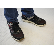 Ein Paar Schnürschuhe aus Textil und Synthetik am Fuß einer Person.