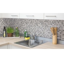 Küchenspüle aus Edelstahl mit Armatur auf einer Arbeitsplatte in einer hellen Küche mit Mosaikfliesen