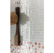 Detailaufnahme einer Wand mit Mosaikfliesen, einem Badeschwamm und einer Bürste