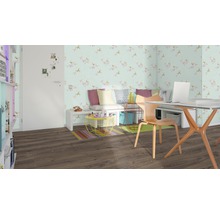 Wohnzimmer mit Schreibtisch, Stuhl, Bank, floraler Tapete und braunem Laminatboden